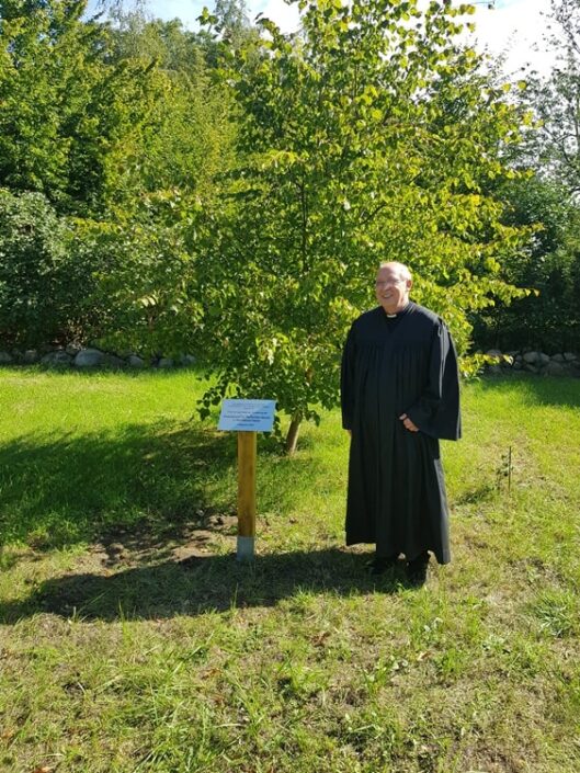 Prädikant Burkhard Fröhlich vor dem Lindenbaum und der Gedenktafel